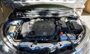 Silnik samochodu z otwartą maską. Widać akumulator, płyny i elementy układu dolotowego. Dowiedz się, jak przeliczyć kW na konie mechaniczne.