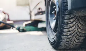 Opony kierunkowe na zimę, gotowe na śnieg. W tle zielony podnośnik samochodowy.