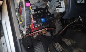 Widok na skrzynkę z bezpiecznikami i przekaźnikami w Audi A4 B6. Widać kolorowe bezpieczniki i wiązki przewodów.