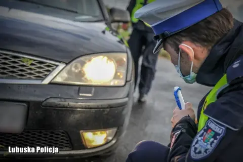 Policjant sprawdza, czy ledy pod autem są legalne. Mundurowy z Lubuskiej Policji bada oświetlenie pojazdu.