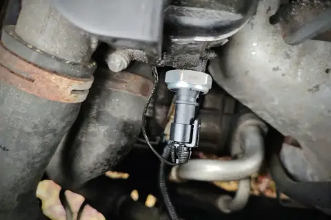 Czujnik ciśnienia oleju 1.9 TDI znajduje się w pobliżu metalowych rur i przewodów silnika.