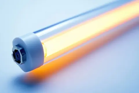 Jasna, długa żarówka LED świeci ciepłym, pomarańczowym światłem. Widoczne są oznaczenia na żarówkach LED na jednym z końców.